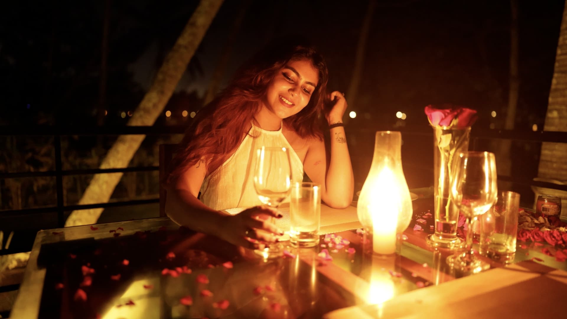 A guest at a candlelit table on the lawn at River Loom, with a lantern and rose petals